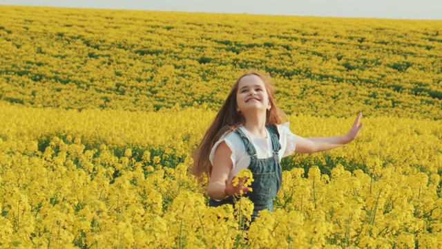 快乐的女孩在黄色的油菜籽地里跳舞。享受美丽的春天明媚的大自然视频素材
