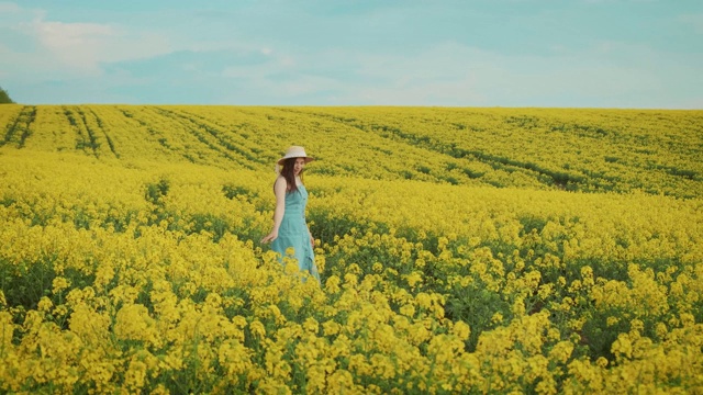 美丽的农妇享受着油菜花的收成，美丽的春日黄花的田野视频下载