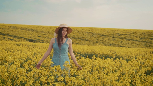 美丽的农妇享受着油菜花的收成，美丽的春日黄花的田野视频下载
