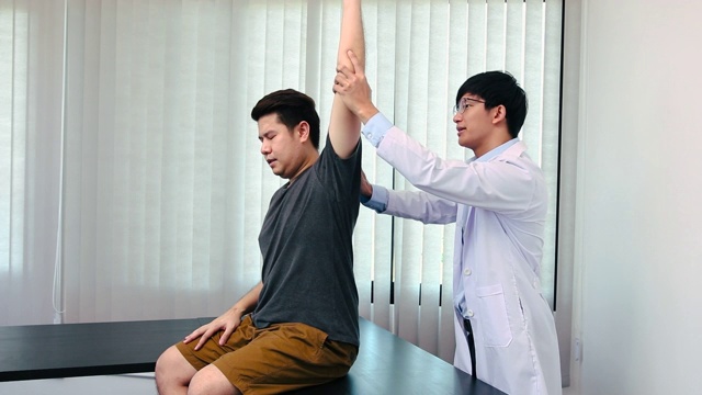 脊椎按摩师在医疗办公室里伸展一个年轻人的手臂视频素材