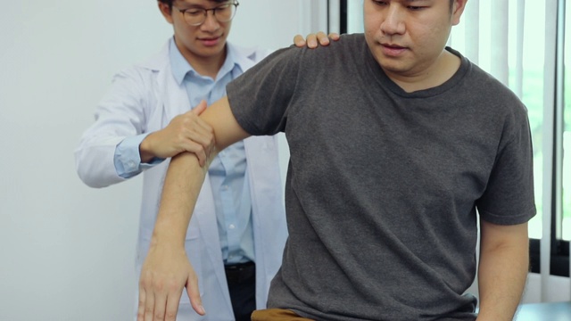理疗师按压病人肩膀检查疼痛。视频素材