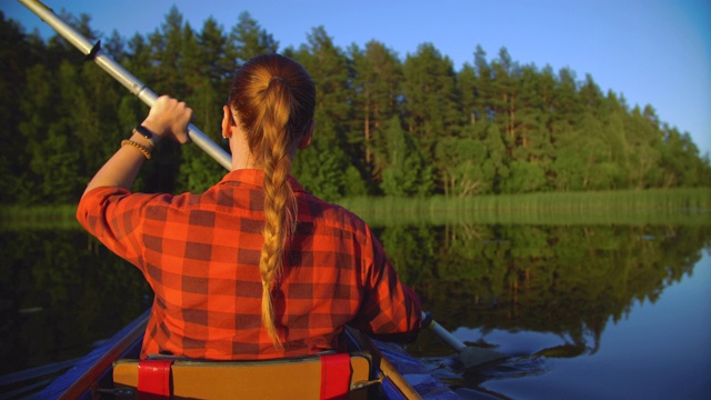 女孩在湖上划着皮艇游泳视频素材