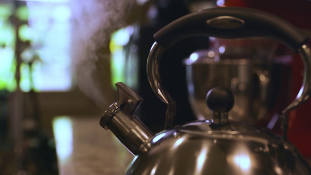 家里炉子上热气腾腾的金属茶壶。不锈钢茶壶或茶壶。视频下载
