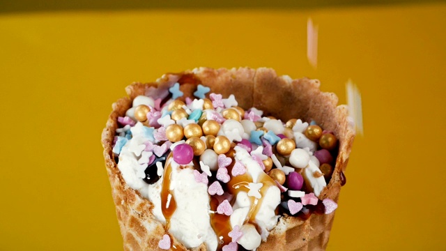 冰淇淋用多种颜色的糕点屑装饰，特写。香草冰淇淋甜筒加上顶部和顶部。视频素材
