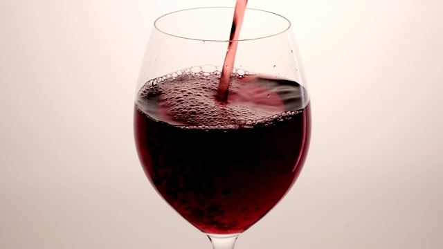 红酒从瓶中倒入高脚杯，背景为白色。玫瑰酒倒入杯中。葡萄酒杯视频素材