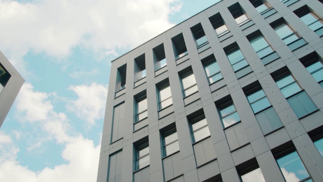 现代商业中心建筑的部分立面是自底向上的视图。天空映照在建筑物的窗户上。视频素材