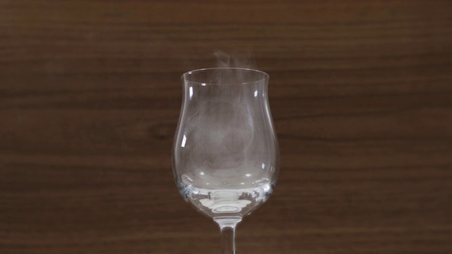 在棕色背景的特写镜头上，烟雾从酒杯上飞离视频下载