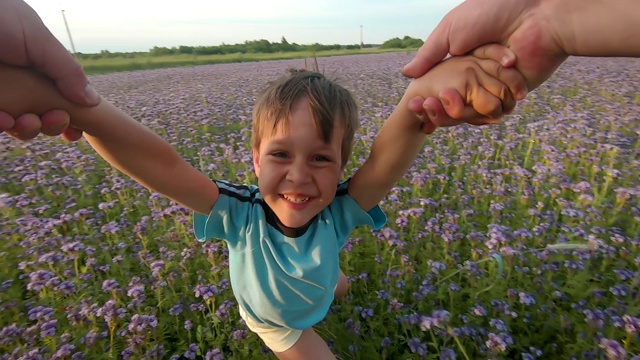 一个快乐的孩子和他的父亲在日落时在草地上玩耍的肖像视频素材