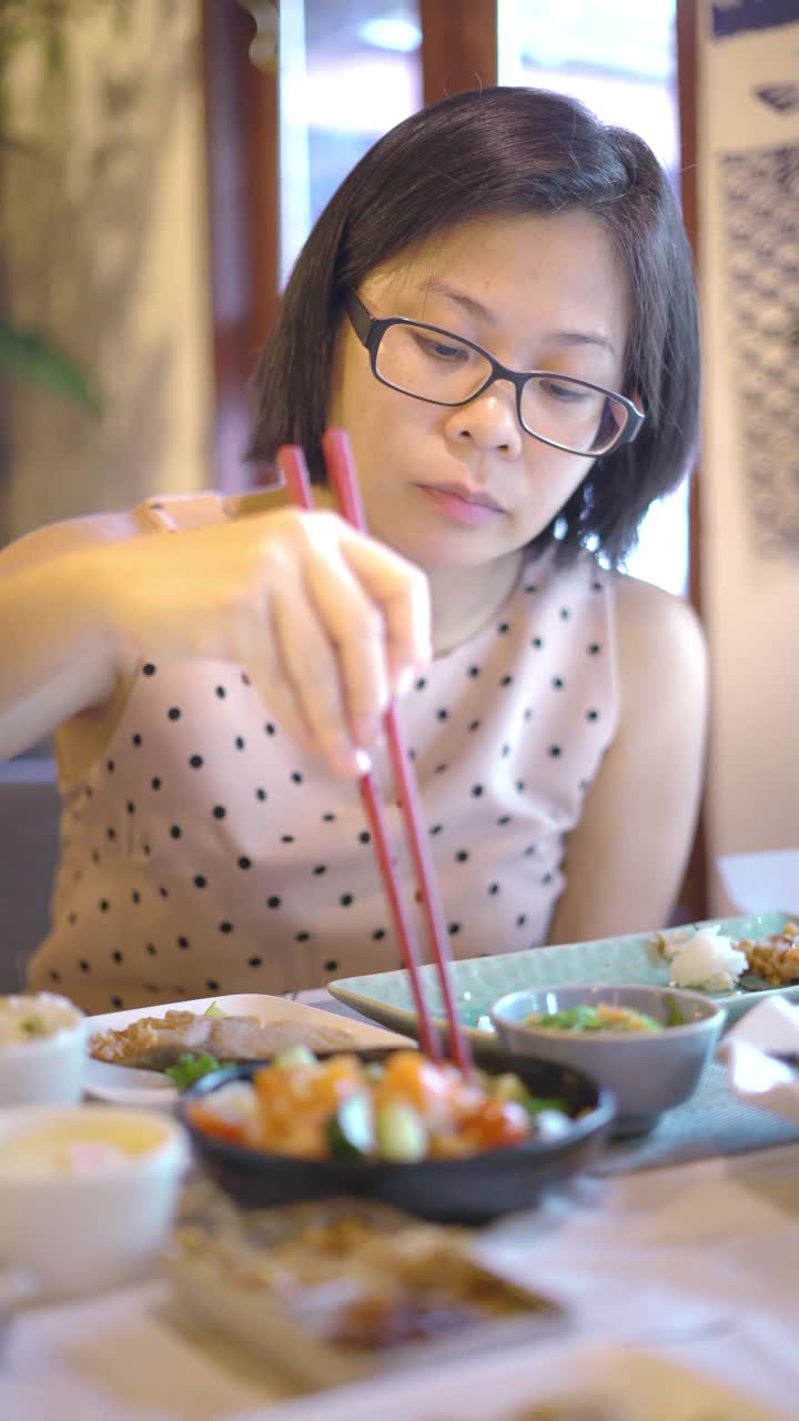垂直拍摄的亚洲妇女享受寿司在日本餐厅。视频素材