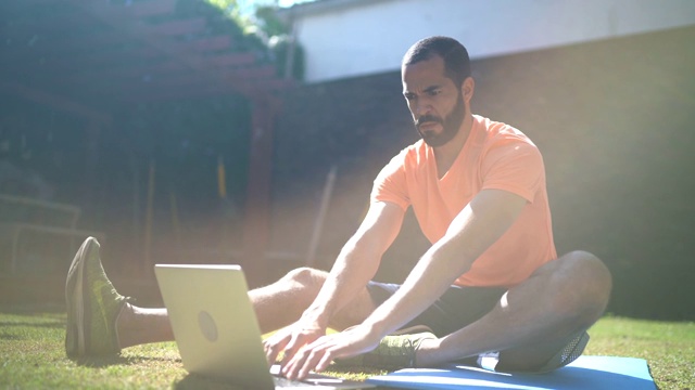 男人在家做运动，在家用笔记本电脑看健身课视频素材