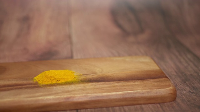 一堆姜黄粉和糖放在棕色桌子上的一块木板上。视频下载