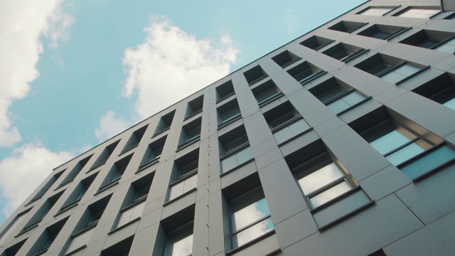 现代商业中心建筑的部分立面是自底向上的视图。天空映照在建筑物的窗户上。视频素材