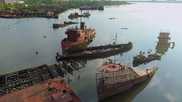 在美国纽约市史泰登岛的船墓地上沉没的生锈的废弃船只。向下看，正上方的航拍视频由无人机，与平移摄像机运动。视频下载
