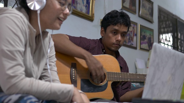亚洲夫妇在他们的空闲时间在家里唱歌和弹吉他视频素材