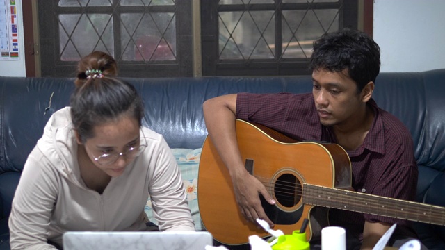 亚洲夫妇在他们的自由日在家唱歌和弹吉他视频素材