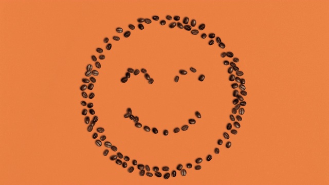 微笑符号形状的咖啡豆在橙色的背景视频下载
