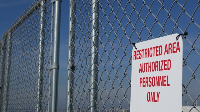 限制区域，授权人员在美国签字。红色字母，金属围栏上的远离警告，美国边境标志。没有侵入通知意味着违规者将被美国法律起诉视频素材