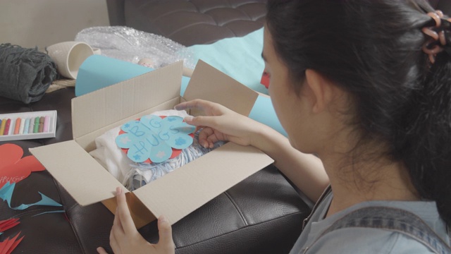俯视图亚洲年轻少女制作手工物品护理包。可爱的女孩正在打包一个女孩盒子准备送给远方的家人或朋友。视频下载