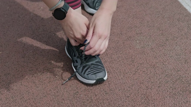 近距离的健身女子系鞋带的马拉松赛道上。4 k, UHD视频素材