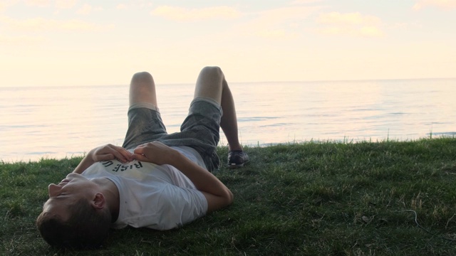 放松的成年人呼吸新鲜空气躺在草地上的海平线在背景视频素材