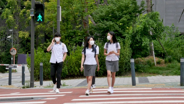 穿着校服的青少年在人行横道上过马路视频素材