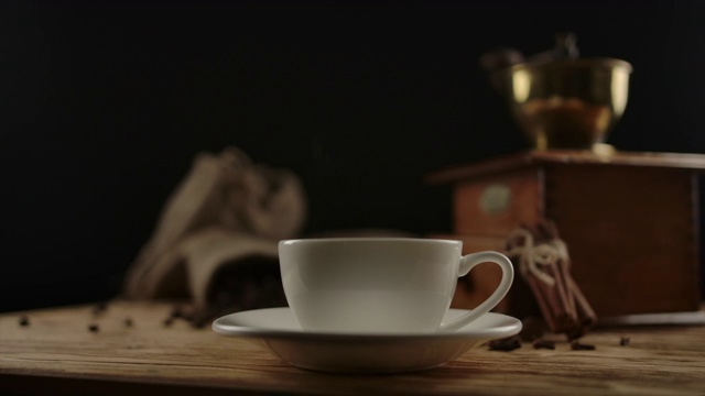 精致的白色瓷杯，在木桌上放着咖啡或茶。缩小视频素材