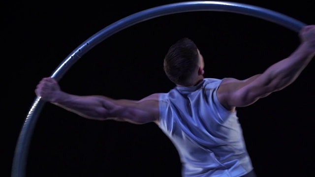 肌肉发达的马戏团艺术家在锡尔轮上慢动作旋转。运动、运动和平衡的概念视频下载