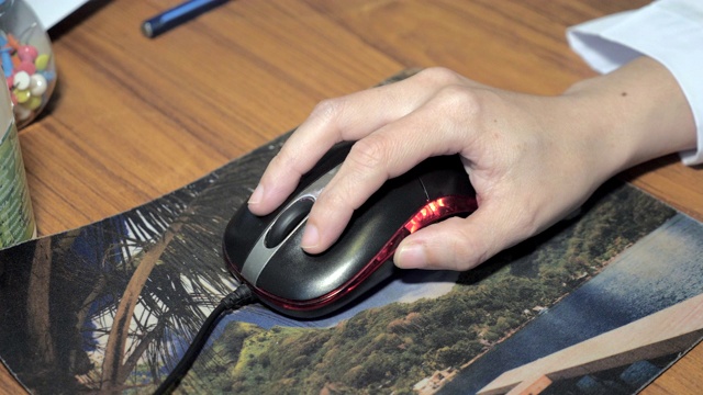 近距离的女人的手使用黑色的电脑鼠标在工作桌上视频下载