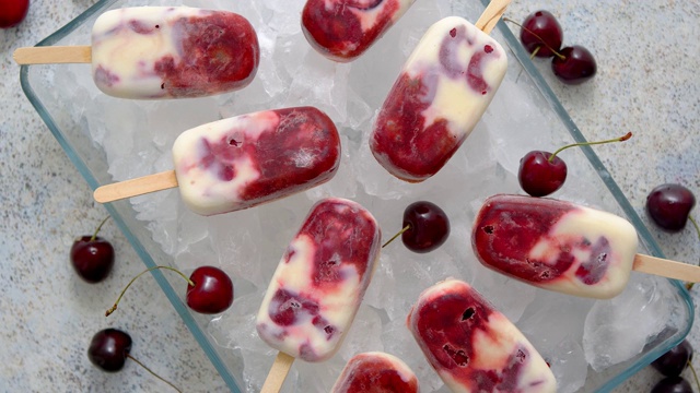 自制美味的樱桃和牛奶冰淇淋冰棒，放在盛满冰块的玻璃托盘上视频素材