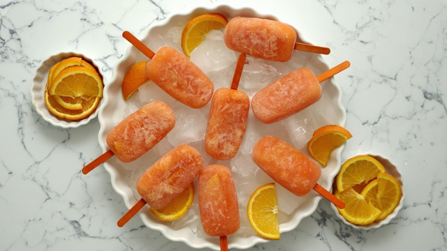 自制多汁橙味冰棒。放置在装有冰块的白色盘子上视频素材