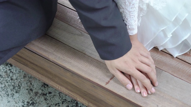 新娘和新郎手牵着手坐在长凳上视频素材