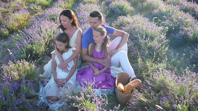 夕阳下，一家人穿着白色的礼服，戴着白色的帽子，站在薰衣草花丛中视频下载