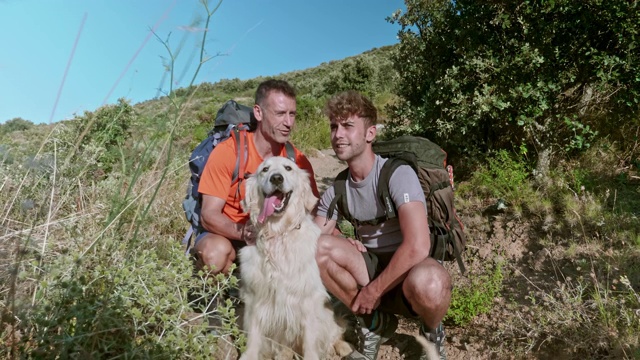 在地中海沿岸徒步旅行时，父亲和成年的儿子与他们的狗狗休息视频素材