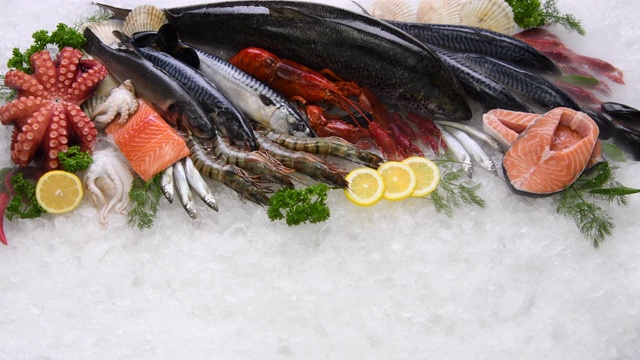 俯视图的各种新鲜鱼和海鲜在冰上与干冰烟。视频素材