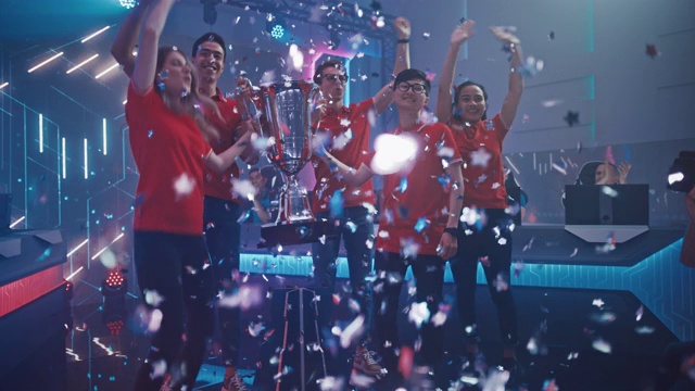 电子游戏锦标赛的不同电竞队伍冠军在大型锦标赛场地庆祝胜利欢呼及举起奖杯。与玩家和粉丝的网络游戏活动。提升慢动作镜头视频素材
