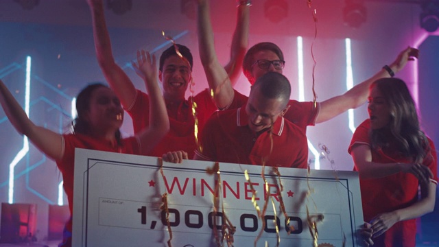 电子游戏锦标赛的不同玩家电竞队冠军庆祝胜利，欢呼和举起$1,000,000奖金颁发支票。冠军竞技场网络游戏在线流媒体视频素材