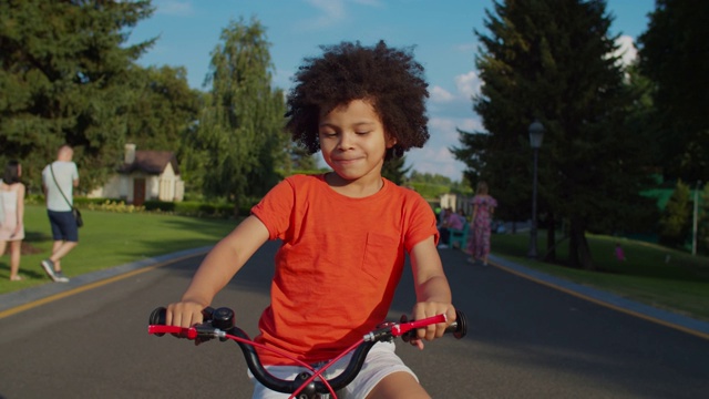 可爱的混合种族男孩有乐趣骑自行车在公园视频素材