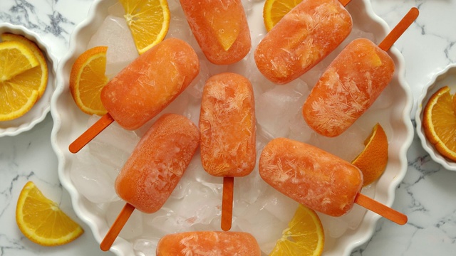 自制多汁橙味冰棒。放置在装有冰块的白色盘子上视频素材