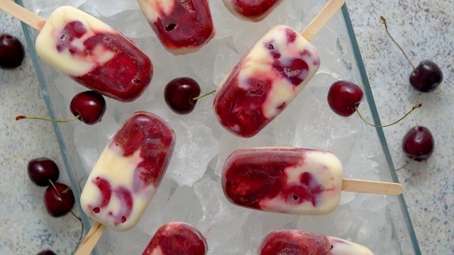 自制美味的樱桃和牛奶冰淇淋冰棒，放在盛满冰块的玻璃托盘上视频素材