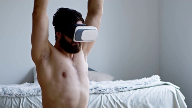 一个戴着VR头盔在家做伸展运动的人视频下载