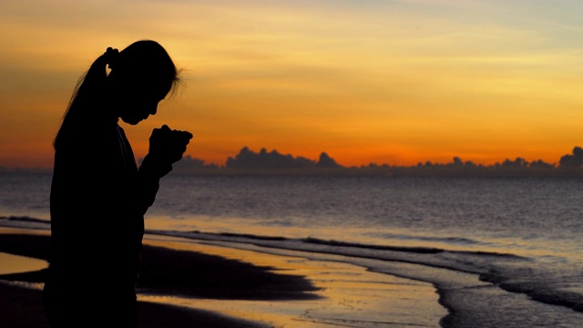 女人祈祷在美丽的日落背景视频下载
