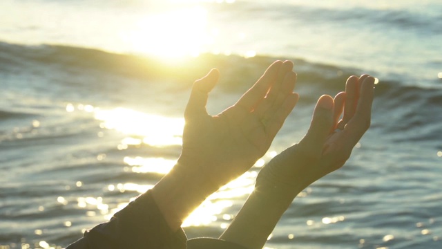 在日落背景下，女人双手祈祷上帝的祝福视频素材