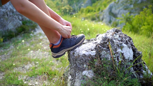 在山上系鞋带的女徒步旅行者视频素材