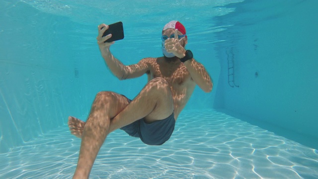 夏日游泳池里，戴着防冠状病毒面罩的男子在水下自拍视频下载