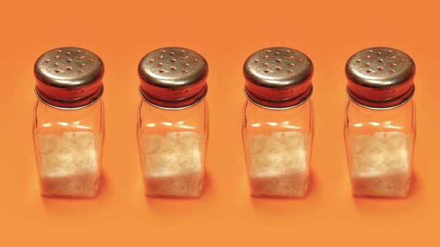 橙色背景上装满白色粉末的盐瓶视频下载
