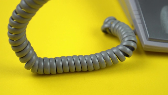 灰色螺旋状的电话线和手机落在黄色的地上视频下载