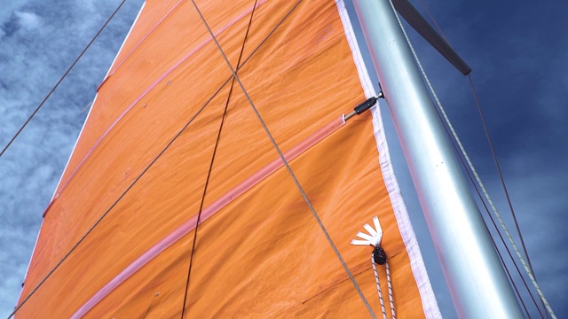 夏天蓝色天空映衬下的橙色游艇主帆视频下载