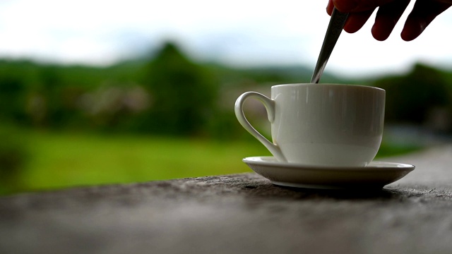 靠近手把勺子在咖啡或茶杯和混合在木桌在早上与山和稻田梯田视频素材