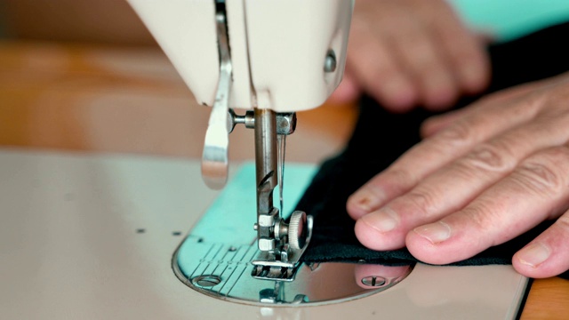 缝纫机的针在动。缝纫机针的特写快速上下移动。裁缝在缝纫车间缝黑色的布料。缝纫织物的过程。视频下载