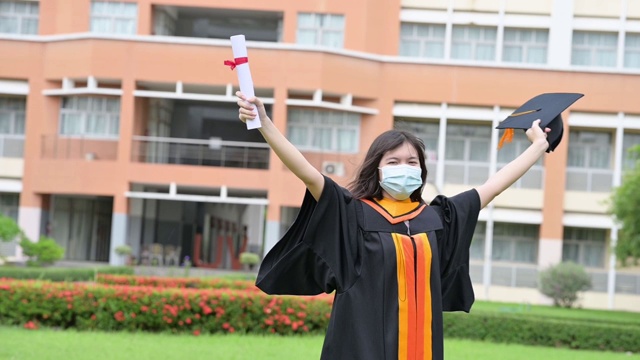 亚洲女毕业生身穿黑色长袍，头戴金色流苏的黑色帽子。拿着文凭微笑着祝贺大学视频素材